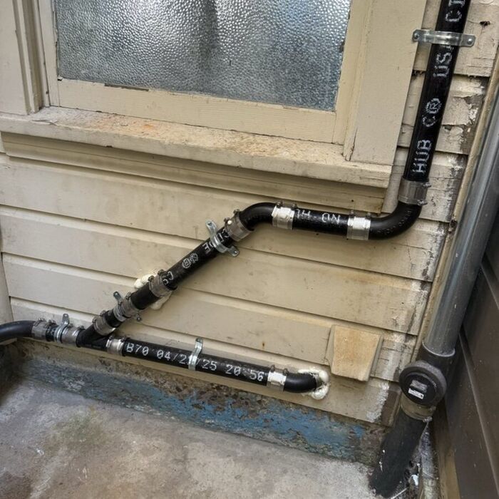 New ABS drain, waste and vent piping routed along an exterior wall with labeled hub couplings