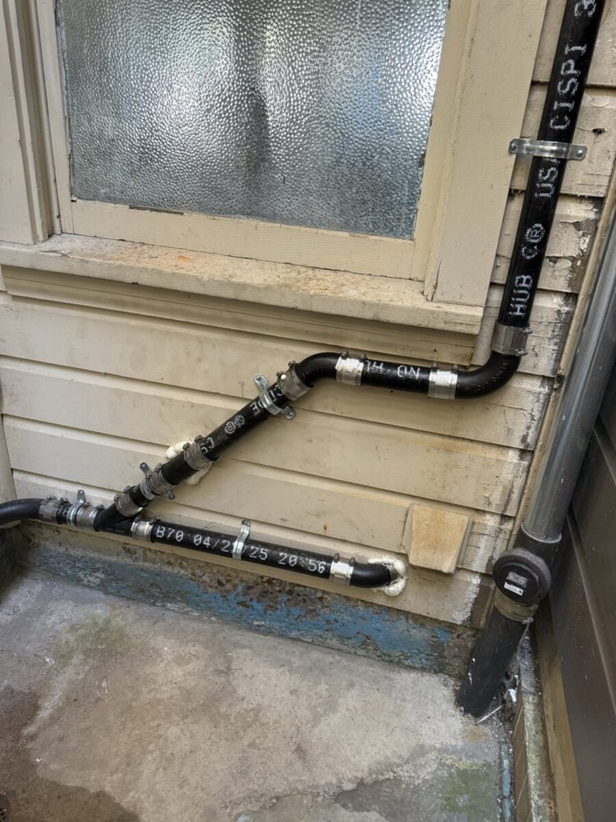 New ABS drain, waste and vent piping routed along an exterior wall with labeled hub couplings